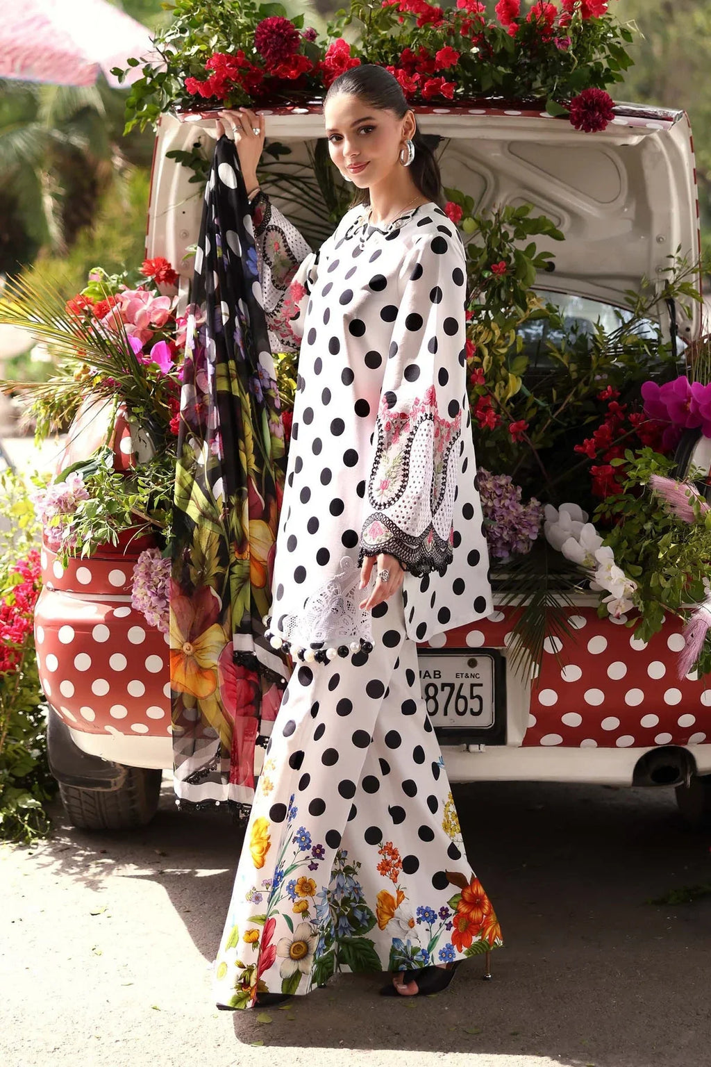 Woman in white polka dot floral print dress with matching dupatta, standing by flower-decorated vintage car