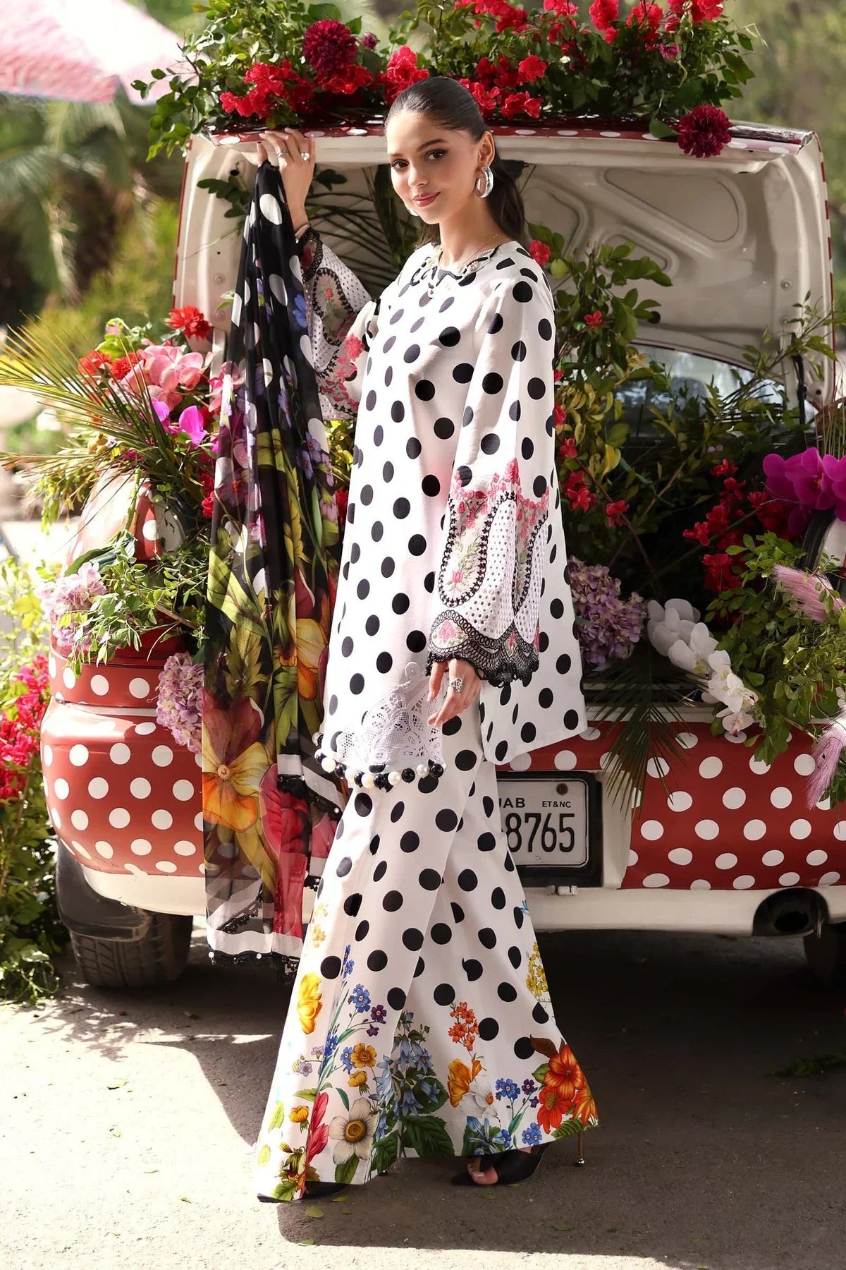Woman in white polka dot floral print dress with matching dupatta, standing by flower-decorated vintage car