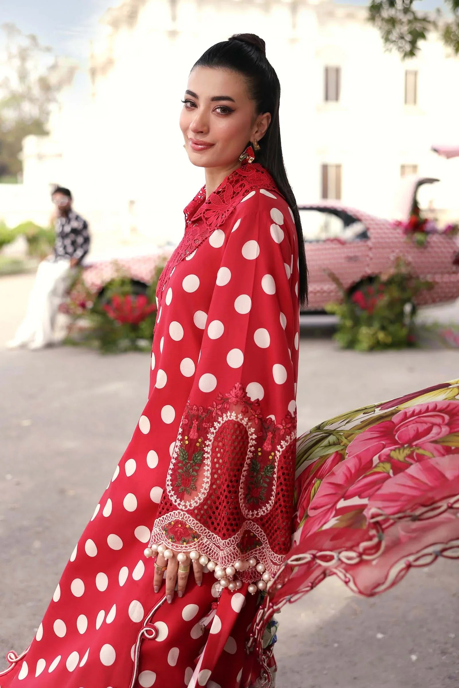 Red polka dot dress with lace and pearl embellishments, floral dupatta, outdoor setting