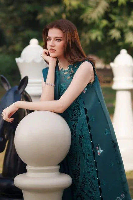Woman in teal embroidered lawn dress leaning on white chess piece outdoors