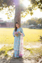 Woman in light blue floral printed kurta with pink dupatta, holding roses under tree in sunny park