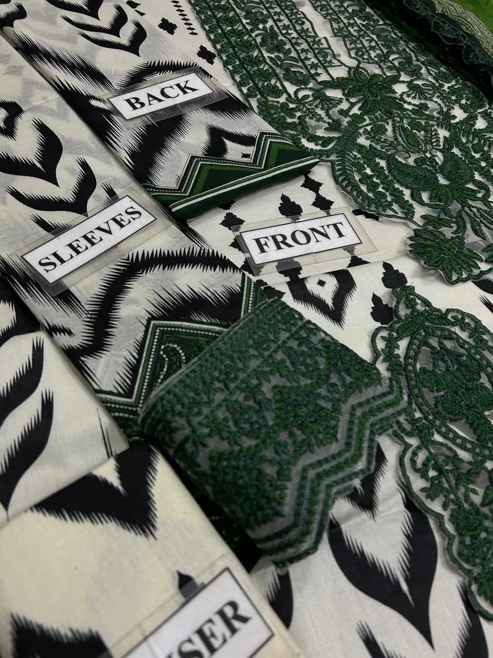 Black and white ikat print dress fabric with green embroidery, labeled front, back, sleeves